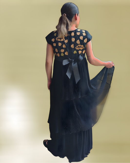 Vestido de lino plisado. Bordado Huixtán color negro, bordado beige, vista posterior en modelo. Detalle de los vuelos.