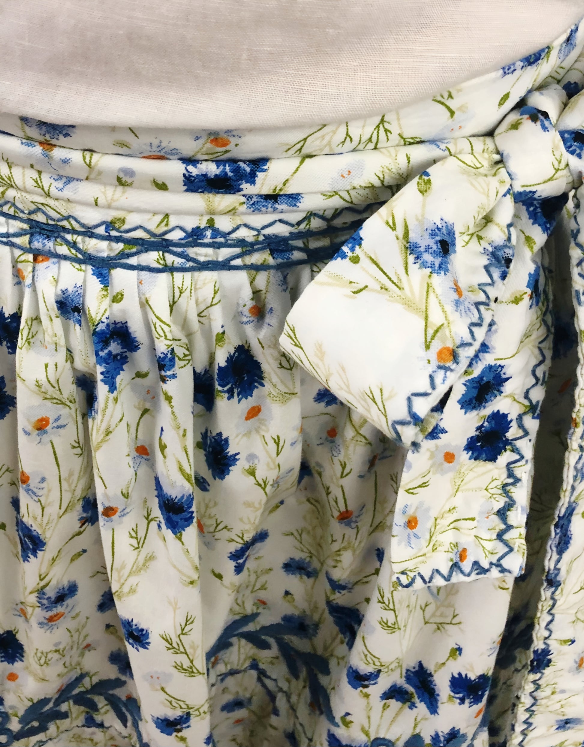 Falda vuelos Aguacatenango color blanco, floreada azul, bordado azul, detalle del moño , tela y bordado.