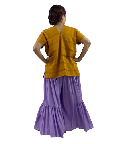 Huipil Rombos Cancuc color mostaza, detalles en lila, vista posterior en modelo.