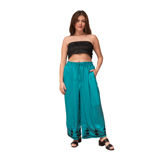 Pantalón satín bordado milpa color turquesa, vista frontal en modelo.