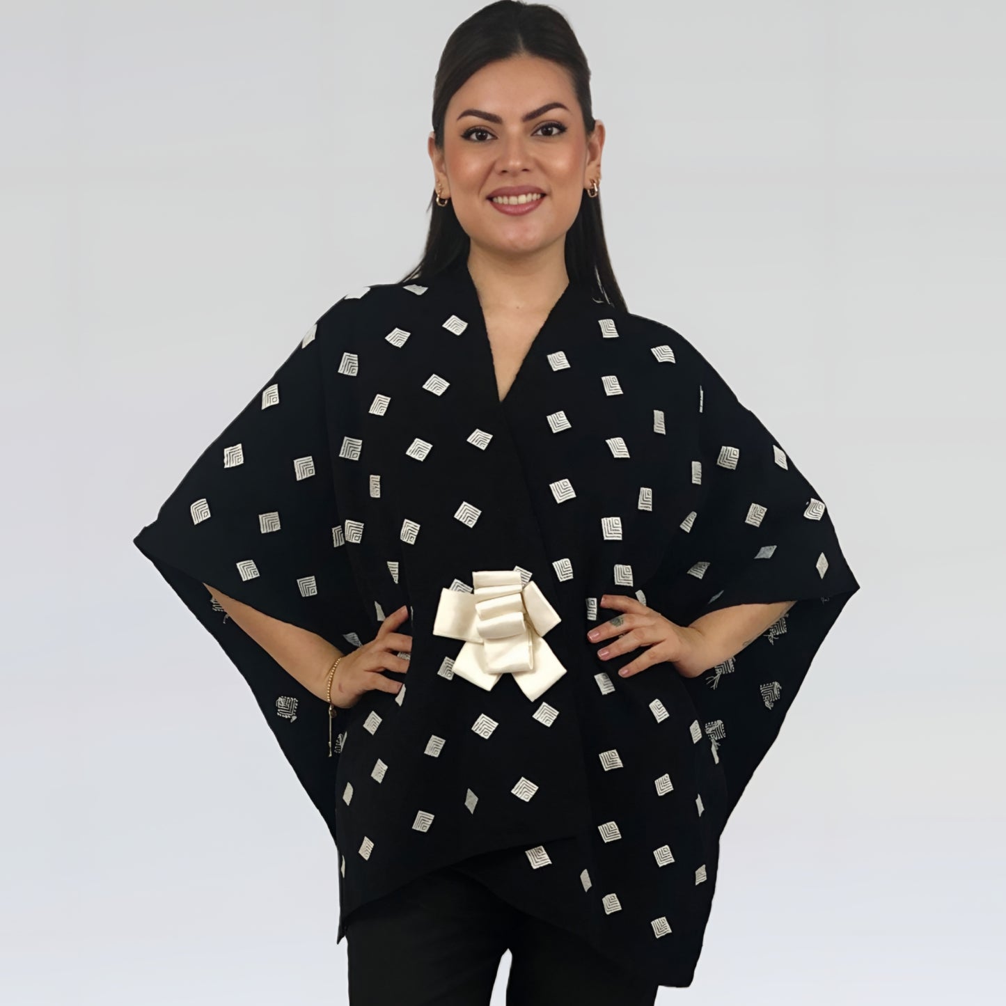Poncho Algodón Con Flor Larrainzar en fondo negro con brocado blanco, vista frontal en modelo.