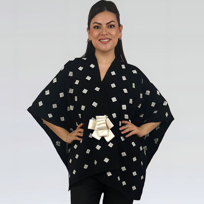 Poncho Algodón Con Flor Larrainzar en fondo negro con brocado blanco, vista frontal en modelo.