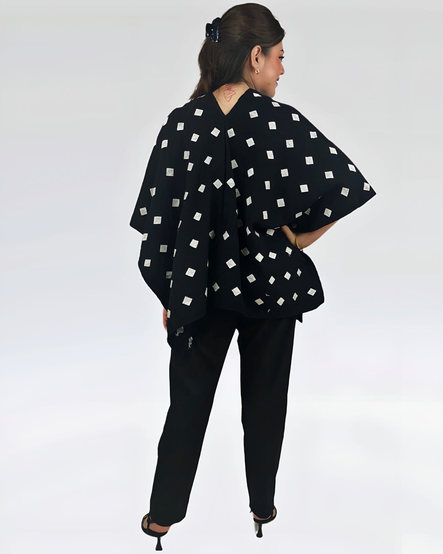 Poncho Algodón Con Flor Larrainzar fndo negro con brocado blanco, vista posterior en modelo.
