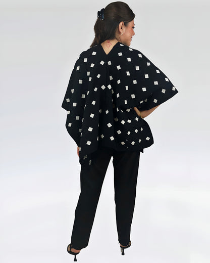 Poncho Algodón Con Flor Larrainzar fndo negro con brocado blanco, vista posterior en modelo.