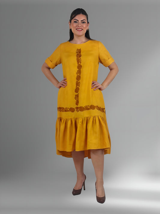 Vestido Acampanado con vuelo bordado a mano Aguacatenango color mostaza, bordado café, vista frontal en modelo.