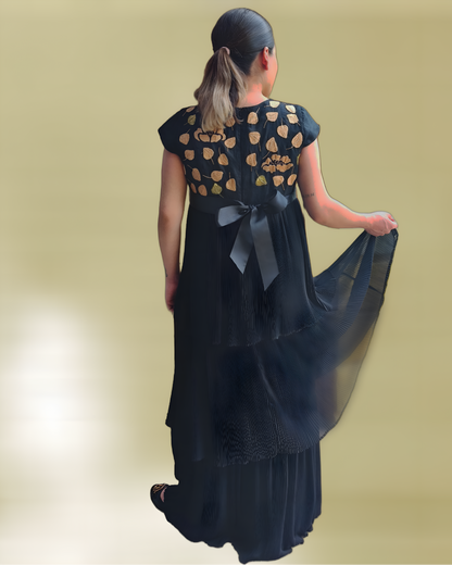 Vestido de lino plisado. Bordado Huixtán color negro, bordado beige, vista posterior en modelo. Detalle de los vuelos.